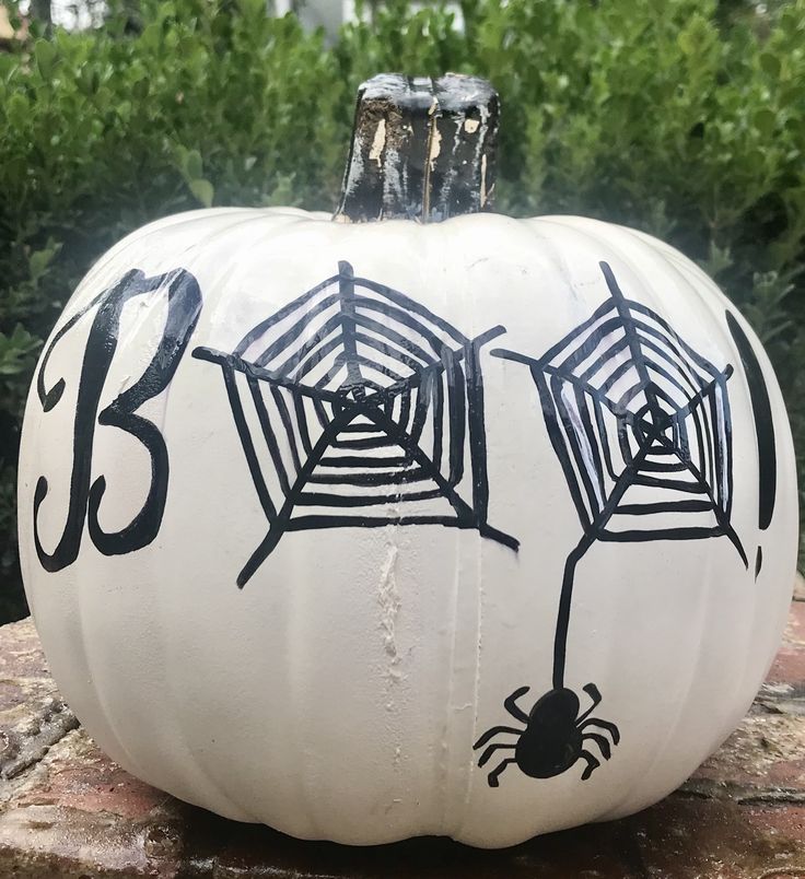 a white pumpkin decorated with a black sharpie, with a word and a spider plus spiderwebs is easy to make