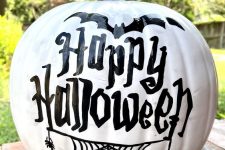 a white pumpkin decorated with black words, bats and spiderwebs is a cool idea for Halloween