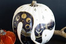 a white pumpkin with a black snake and gold decor on it is a cool idea for a Halloween pumpkin