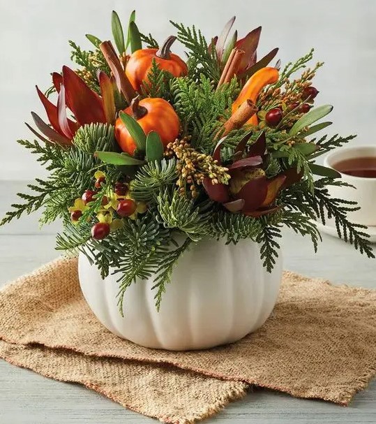 a white pumpkin with faux blooms, berries, greenery and faux pumpkins and gourds for the fall