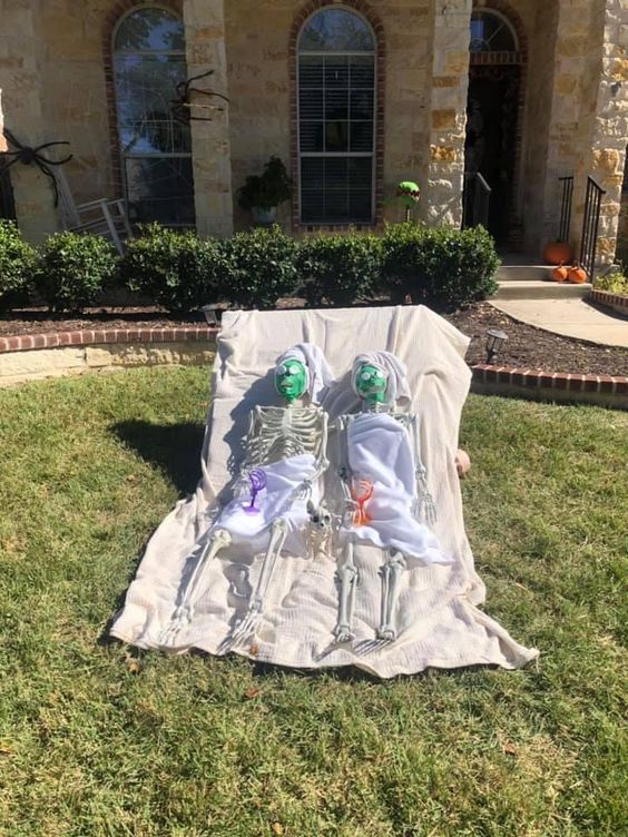 a yard skeleton scene with two skeletons relaxing with masks on their faces is a cool idea for Halloween
