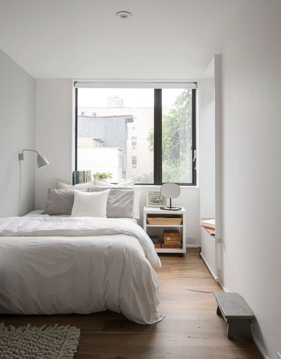 an airy and welcoming small bedroom in white, with white furniture, a tiny bench, a nightstand and a daybed by the window