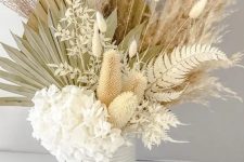 an airy centerpiece of white hydrangeas, bunny tails, dried fronds and leaves is a textural and very creative idea