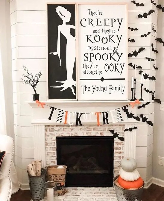 an elegant contrasting fireplace with two monochromatic signs, bats, a bright bunting and stacked pumpkins