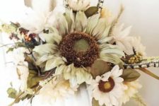 an elegant fall centerpiece of a white pumpkin, faux blooms, foliage and dried touches is a stylish centerpiece idea
