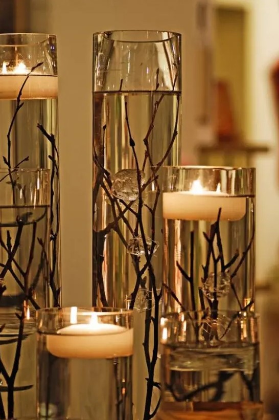 an exquisite fall decoration of tall vases with twigs and branches plus floating candles is lovely and chic