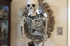 an oval mirror in a whimsical frame, with a glitter and sequin skeleton, is a cool Halloween decoration to make