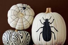 black and white pumpkins decorated for Halloween with a black sharpie, with a bug, some pattern and spiders are awesome