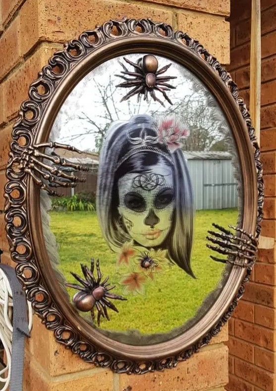 bold Halloween mirror decor with a sugar skull, skeleton hands and copper spiders is a cool and bright idea