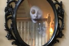 dramatic Halloween mirror decor with a ghost face inside it is a cool decoration for any Halloween space