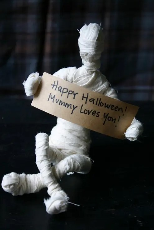 fun tabletop mummy decor with a sign is a cool idea to DIY for the coming Halloween to add a bit of fun