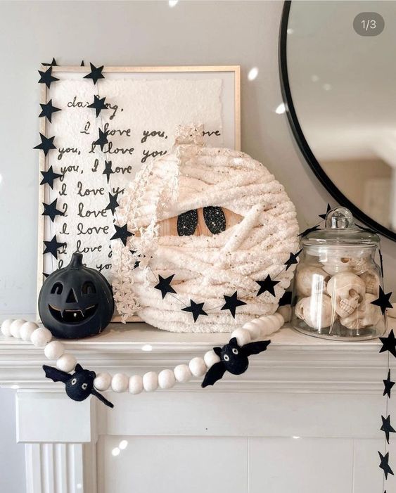 lovely and cool Halloween mantel decor with a round mummy, a black pumpkin, fun garlands and banners is wow