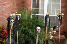 outdoor Halloween decor with skulls on sticks that turn into lanterns at night is a cool idea to rock