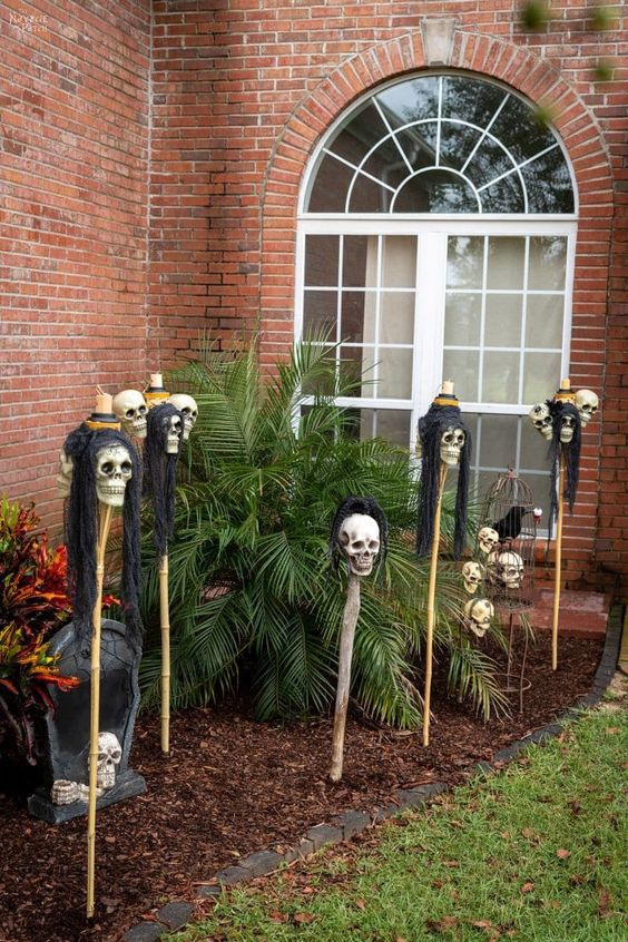 outdoor Halloween decor with skulls on sticks that turn into lanterns at night is a cool idea to rock