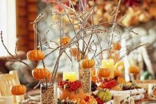 tall glasses with grain, twigs and branches with pumpkins, pinecones, faux gourds and veggies and berries compose a chic fall centerpiece
