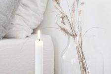 Nordic fall decor with a wooden candleholder with a candle, a clear vase and dried grasses is cool and simple