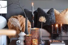 Nordic fall living room done in grey, black and orange, with candles, catchy lanterns and a gallery wall plus branches