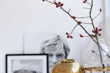 Scandinavian fall decor with a clear vase with branches, a gold vase and teaware is a cool idea for any space