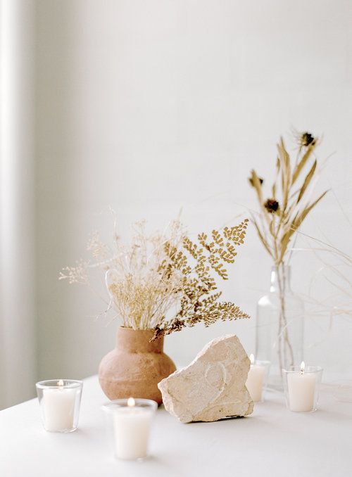 Scandinavian fall decor with rock, pillar candles, vases with dried blooms and grasses is cool and laconic