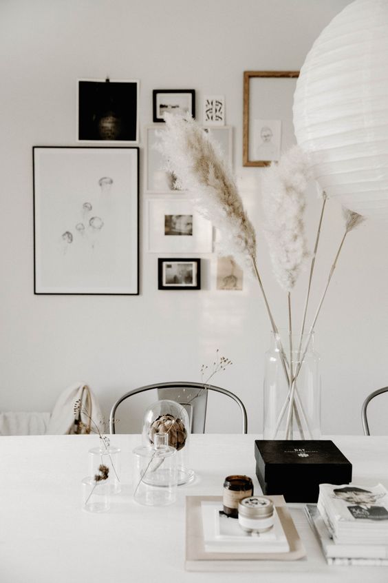 Scandinavian table decor with pampas grass in a clear vase, an artichoke, some branches in clear vases