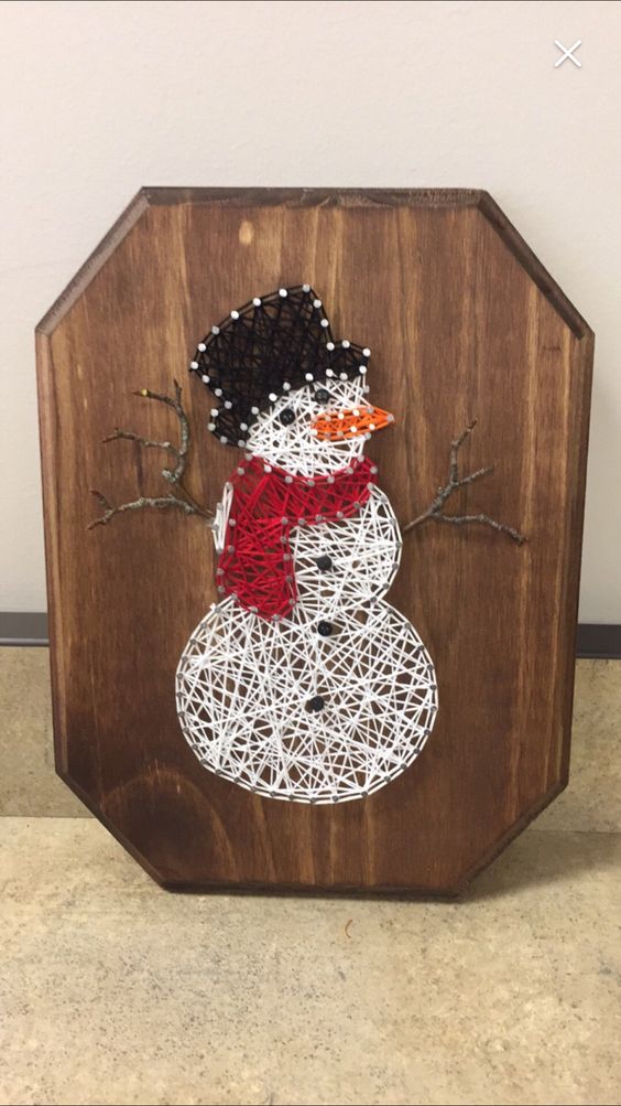 a Christmas string art piece with a snowman done with yarn is a very cool and fun decor idea to try