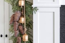 a Christmas table runner with evergreens, pinecones and bells is a cool decoration for a cozy rustic feel