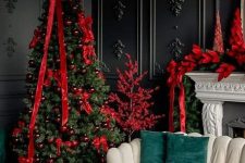 a Christmas tree styled with red ornaments and ribbons, red poinsettias and a red tree make the space cooler