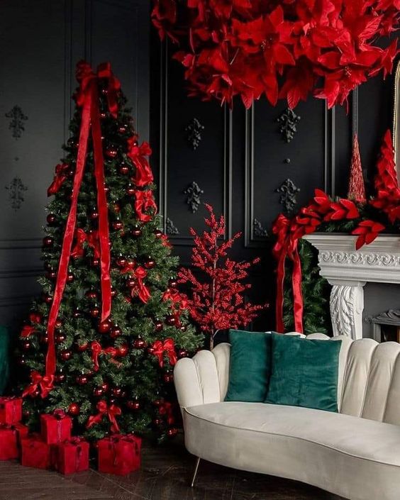 a Christmas tree styled with red ornaments and ribbons, red poinsettias and a red tree make the space cooler