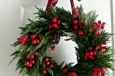 a Christmas wreath of evergreens and red berries and a red printed ribbon is a cool idea for holiday decor