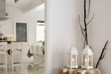 a Nordic decoration of a wooden slab table, a faux fur rug, branches and white candle lanterns