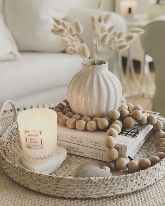 a Scandinavian fall arrangement with a decorative tray, wooden beads, a fluted vase with bunny tails, a candle and coasters