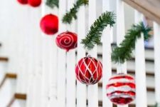 a banister decorated with evergreens and red and silver ornaments is a beautiful idea for Christmas