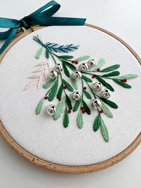a beautiful Christmas ornament of an embroidery hoop, with embroidered leaves, berries and bells