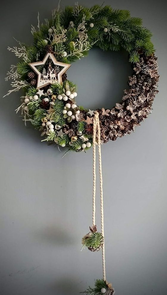 a beautiful Christmas wreath of evergreens and pinecones, wooden stars, white berries, a star with deer and hanging pinecones