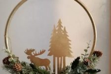 a beautiful embroidery hoop Christmas wreath of evergreens, pinecones, plywood trees and a moose plus a ribbon bow