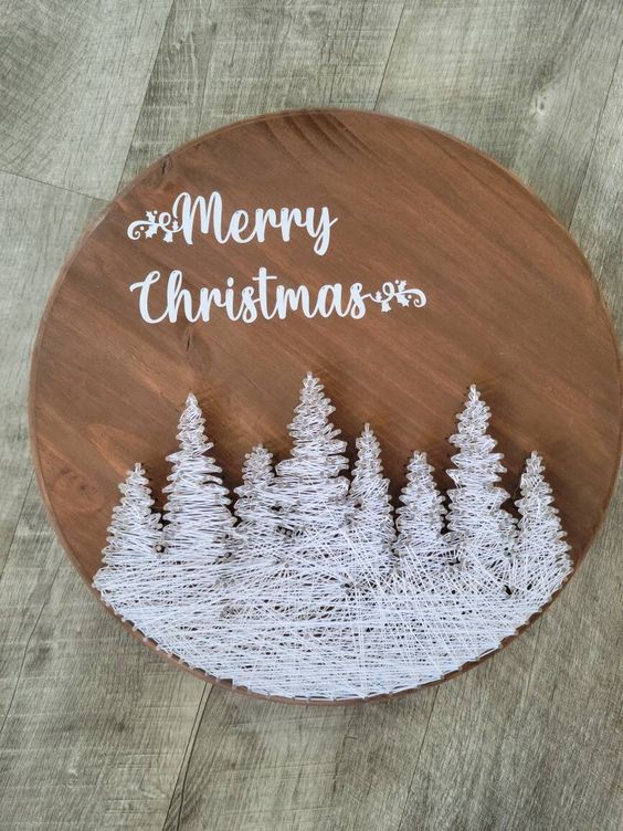 a beautiful round Christmas sign with string art snowy trees and calligraphy is amazing