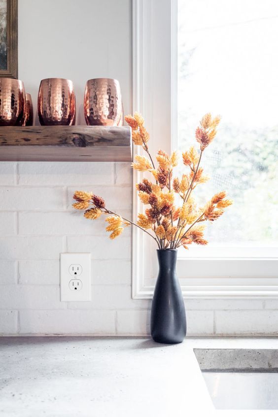 a black vase with dried branches is a cool idea for Scandinavian decor in the fall