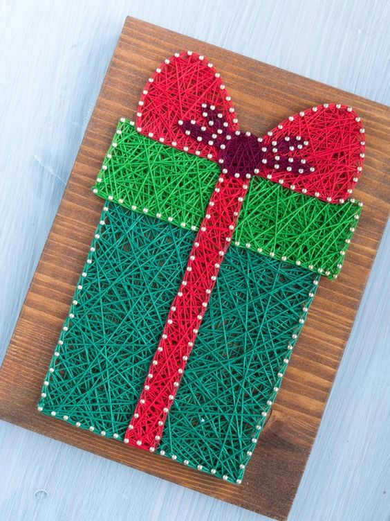a bright Christmas string art piece showing a gift box, done in red and green, is a cool and catchy decor idea