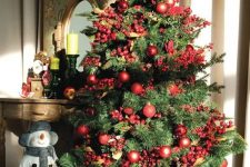 a bright Christmas tree styled with red ornaments and faux berries plus pinecones looks amazing