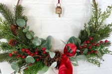 a bright Christmas wreath with evergreen, greenery, pinecones, berries, a red ribbon bow is amazing
