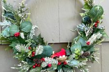 a bright holiday wreath with leaves, snowy evergreens, berires, pinecones is a cool modern decor idea