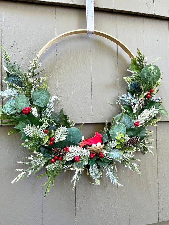 a bright holiday wreath with leaves, snowy evergreens, berires, pinecones is a cool modern decor idea