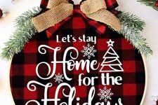 a cozy Christmas wreath with red plaid fabric, white letters, evergreens and a couple of bows on top is amazing