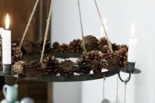 a creative pendant chandelier with pinecones and candles plus some paper decorations hanging down for a natural feel