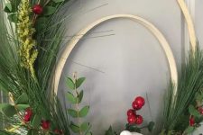 a double embroidery hoop Christmas wreath of evergreens, berries, snowy pinecones, a bird and a ribbon bow is lovely
