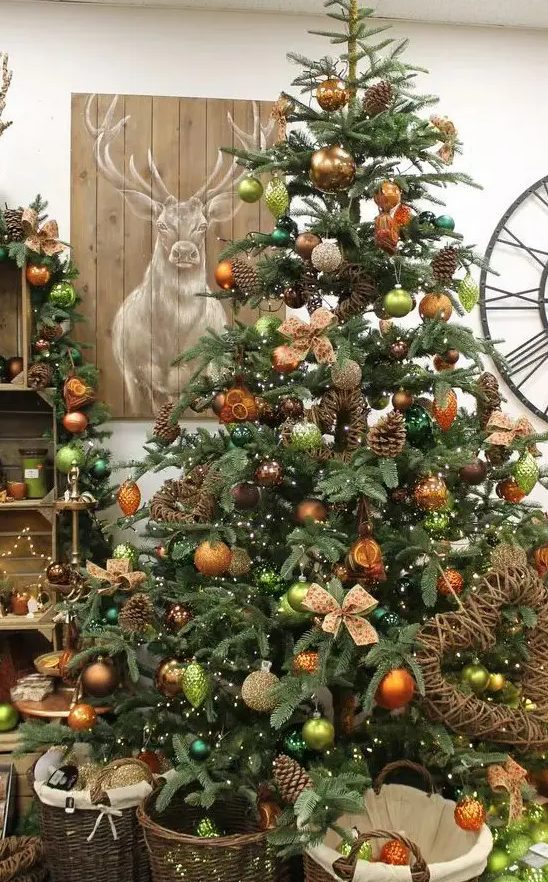 a fabulous woodland glam Christmas tree with copper, orange, light green ornaents, pinecones, vines and vine decorations is amazing