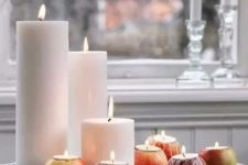 a fall Nordic centerpiece of a tray with pillar candles and apples with candles isnerted inside is a very easy decoration