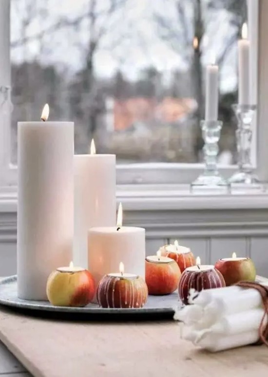 a fall Nordic centerpiece of a tray with pillar candles and apples with candles isnerted inside is a very easy decoration
