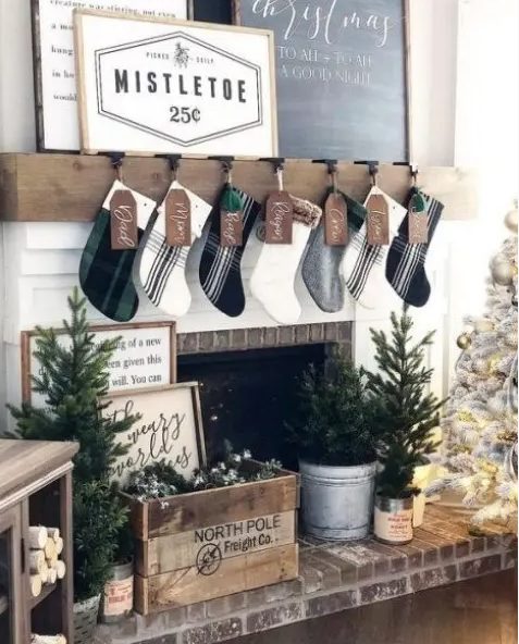 a farmhouse living room with plaid stockings, a crate with evergreens, mini Christmas trees and a neutral Christmas tree