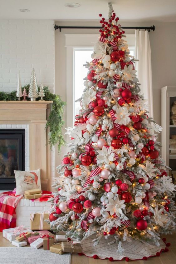 a flocked Christmas tree with red ribbon, white blooms, lights, red and blush ornaments looks spectacular